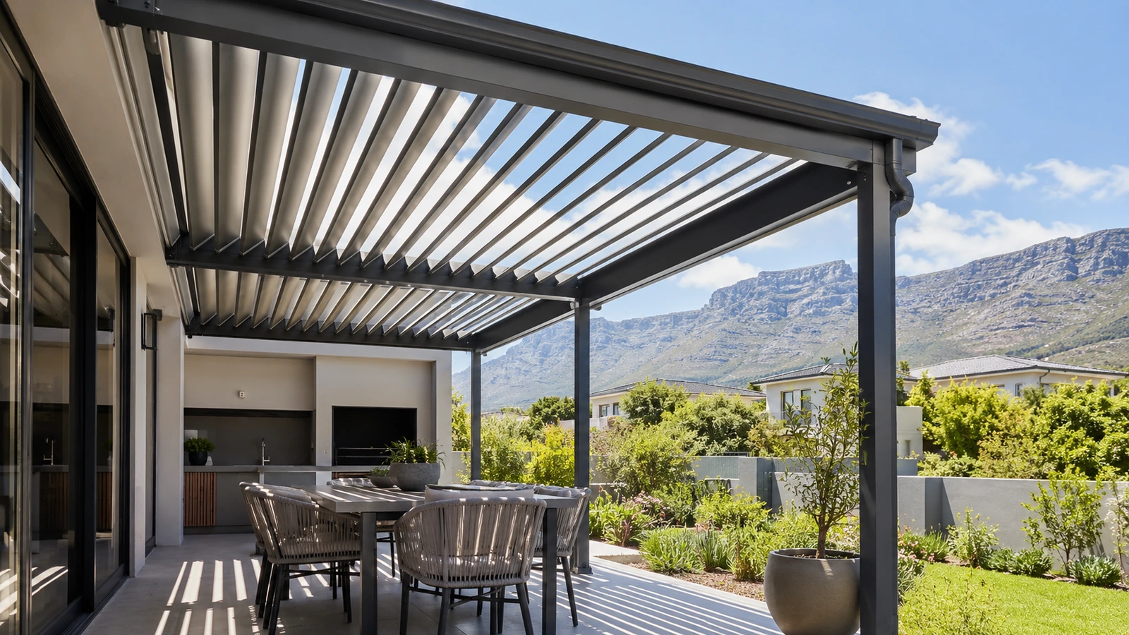 Adjustable aluminium louvre awning with open blades over a paved residential patio