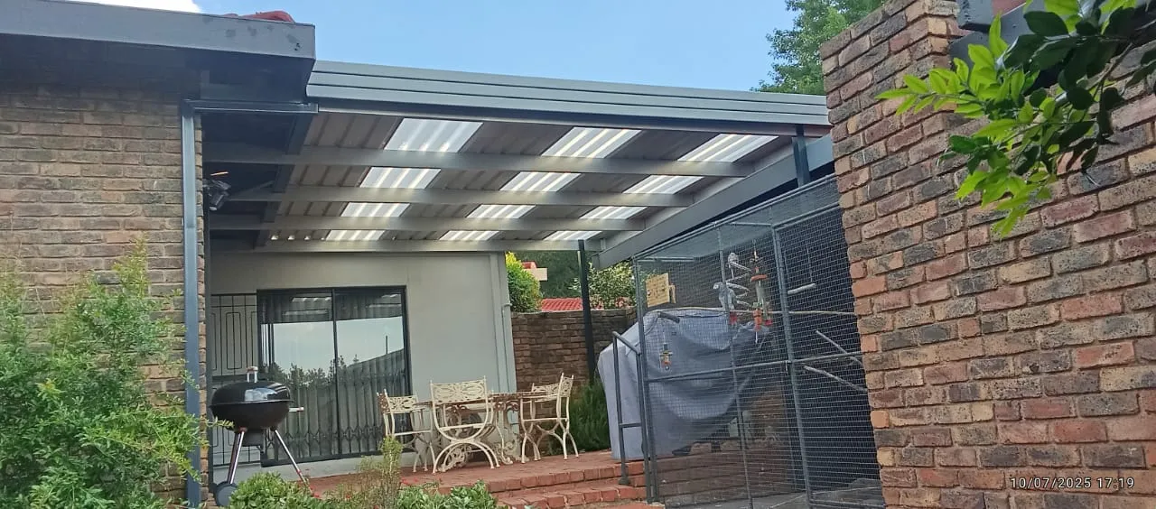 Charcoal IBR awning with clear polycarbonate panels over a brick braai courtyard