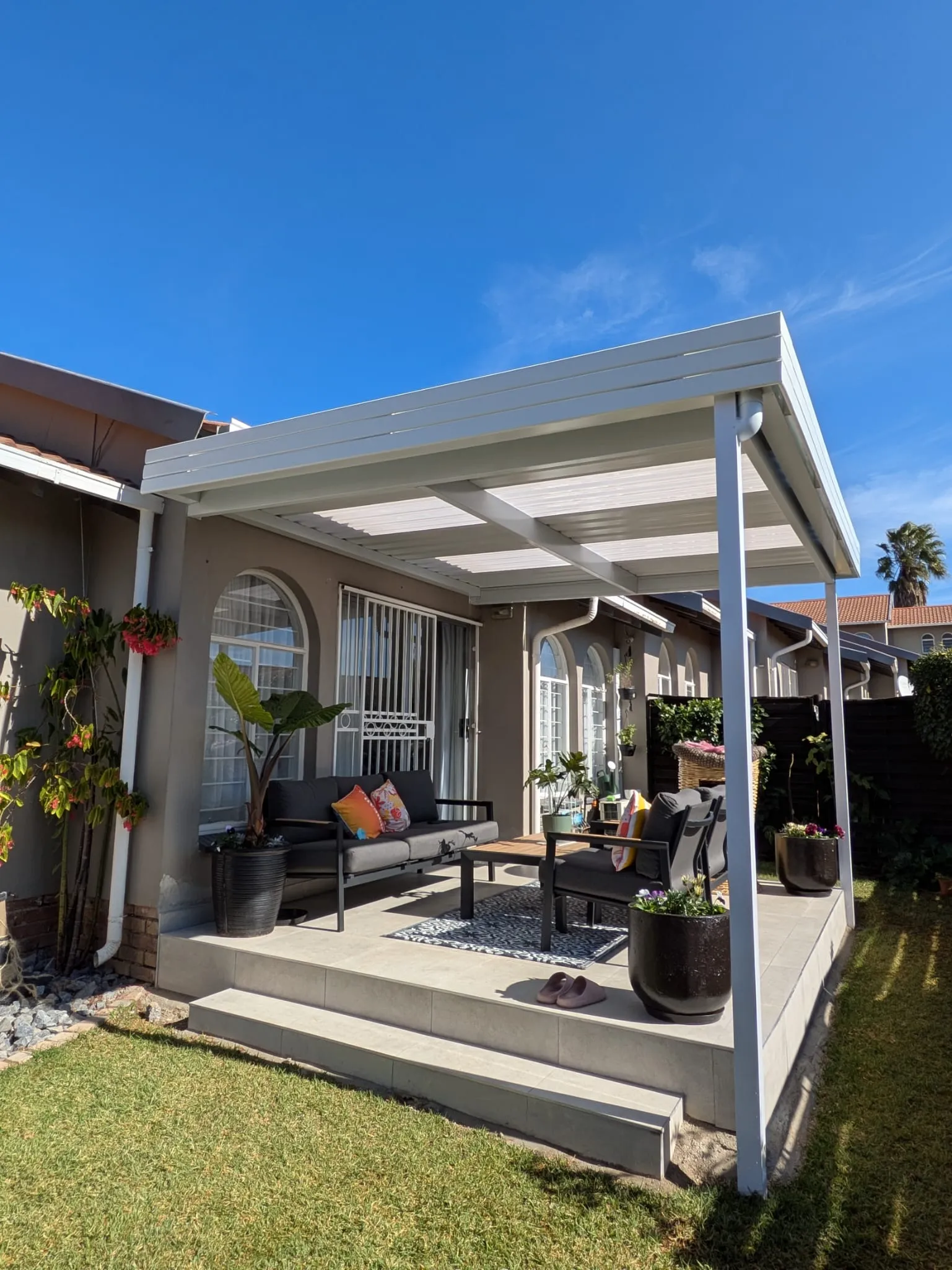 White fixed IBR patio roof covering an outdoor lounge