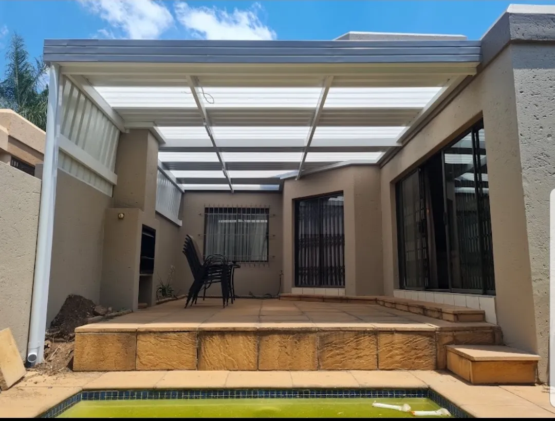 White IBR awning with clear panels covering a poolside courtyard patio