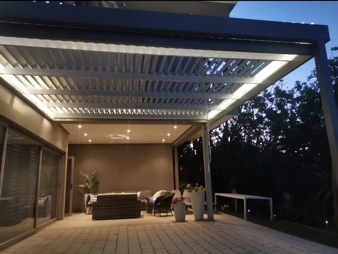 Louvre awning with integrated LED lighting over a furnished patio at dusk